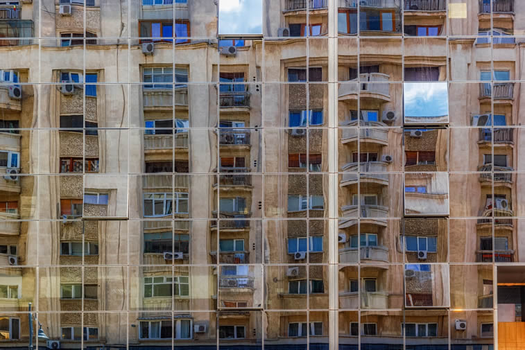 old building in bucharest reflected in the windows of new tower