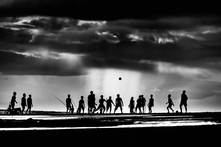 children playing on the Pekutatan beach in Bali silhouettes stormy clouds