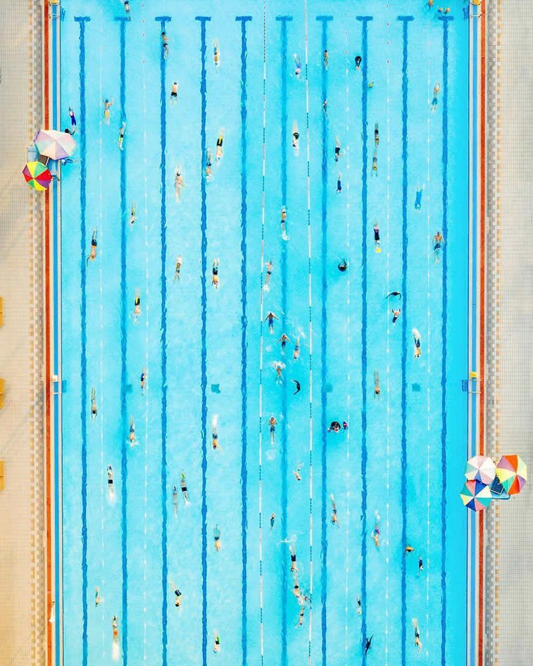 swimming pool swimmers birds eye umbrellas