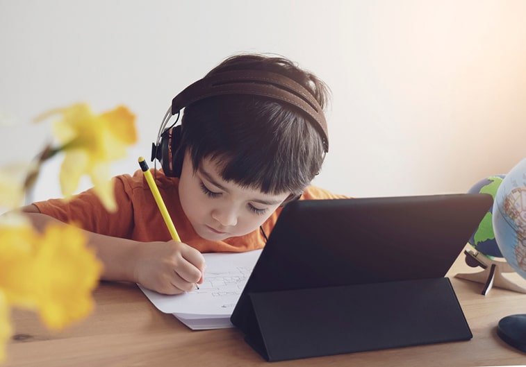 boy writing in front of a laptop