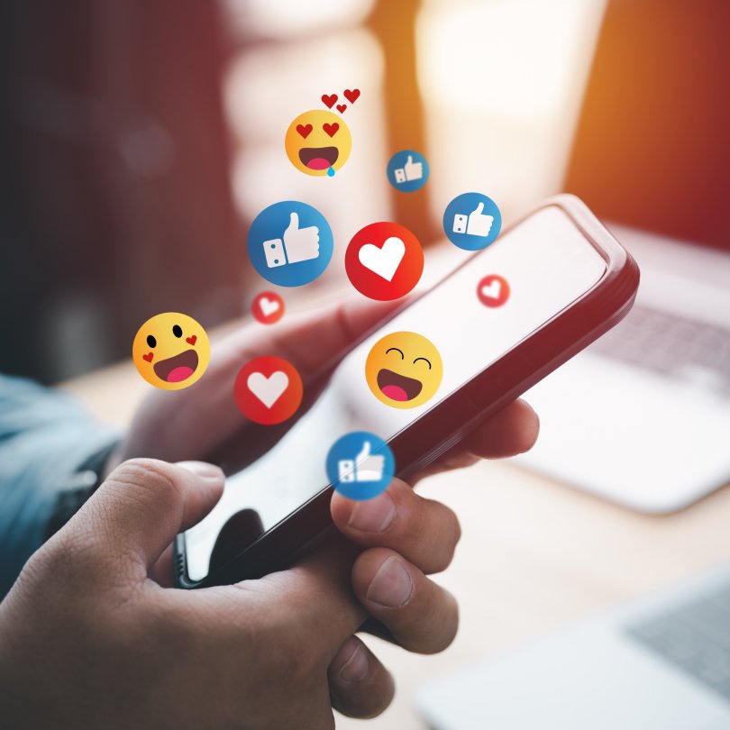 Social media emojis on phone screen.