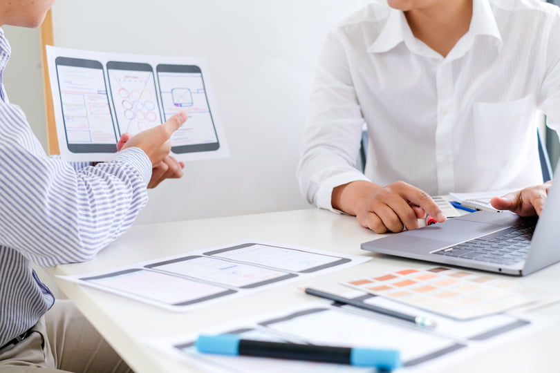 Dva čoveka sede u kancelariji i planiraju mobilnu optimizaciju sajta tokom redizajna.